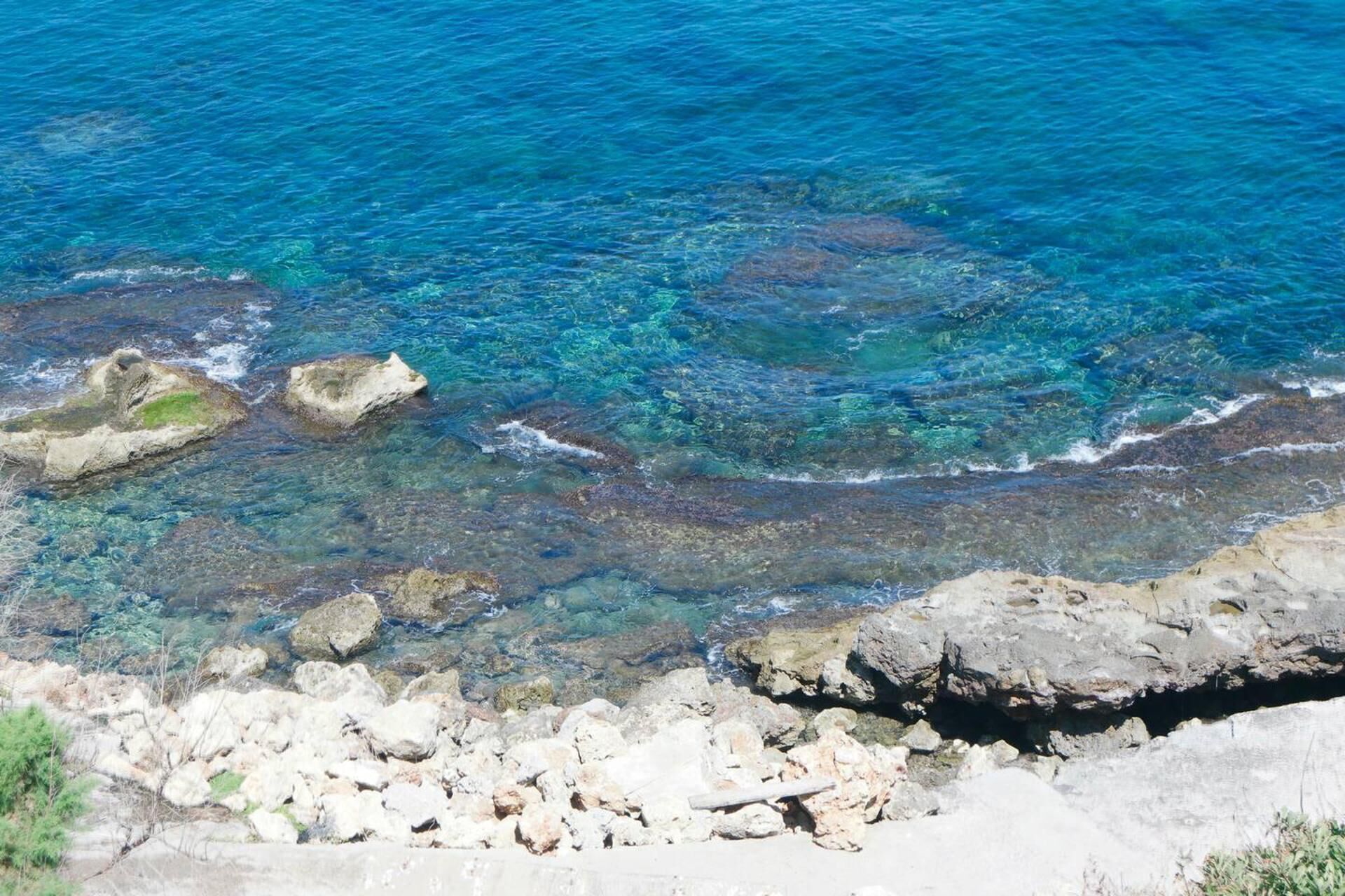 A rocky shoreline with clear blue water.