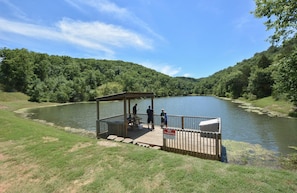 A wooden dock with a covered seating area overlooking a lake, surrounded by lush greenery. - Westcreek Lodge @ Notch-vaulted Ceilings, 2 Pools, Private Lake, 1 Mile to Sdc! (Branson West)