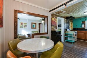 A dining area with a round table and chairs, a kitchen with wooden cabinets, and a large mirror on the wall. - Downtown House in Historic Branson - Awesome Location (Branson)