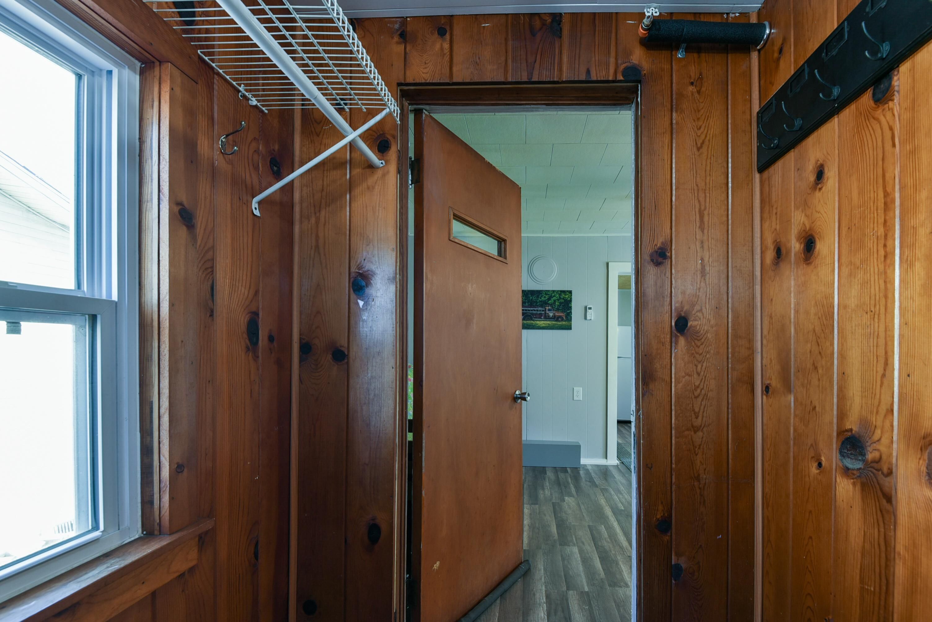 Interior de madera con una puerta que da a otra habitación, una ventana y una rejilla en el techo.