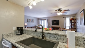 A kitchen with granite countertops, a stainless steel sink, a coffee maker, and a ceiling fan. - Matchplay - Resort Amenities W/ Indoor Pool - Comfort Meets Style and Fun! (Branson)