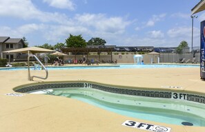 Piscina com marcação de profundidade de 3 pés, cadeiras de espreguiçadeira e guarda-sóis.