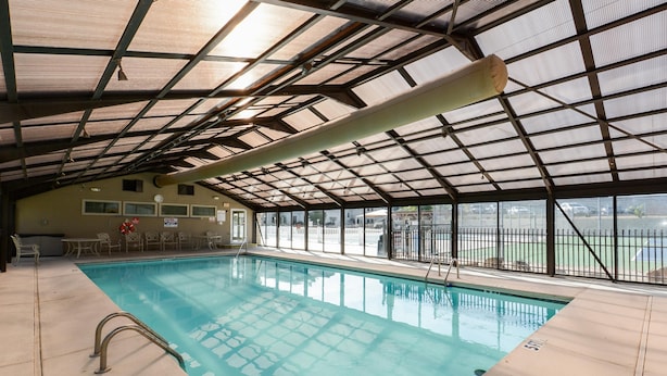 An indoor swimming pool with a metal roof, clear glass panels, and a view of the outside. - Matchplay - Resort Amenities W/ Indoor Pool - Comfort Meets Style and Fun! (Branson)