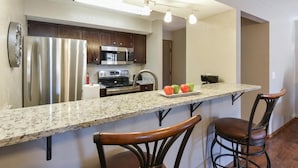 A modern kitchen with stainless steel appliances, a granite countertop, and bar stools. - Matchplay - Resort Amenities W/ Indoor Pool - Comfort Meets Style and Fun! (Branson)
