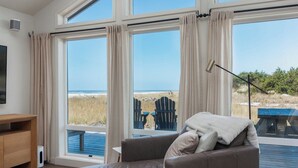 Una habitación con un amplio ventanal con vista a la playa, un sofá de cuero y un escritorio de madera.