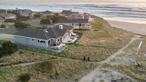 Una zona residencial costera con casas cerca de la playa, cielo despejado y algunas personas caminando.