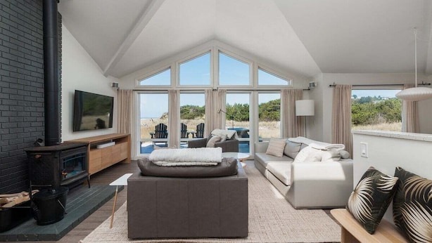 Una sala de estar moderna con chimenea, ventanas amplias y vistas al exterior.