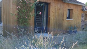 A wooden house with a dark door, a small window, and a garden with lavender and roses. - La chouett'chambre" bed and breakfast (Les Hermites)