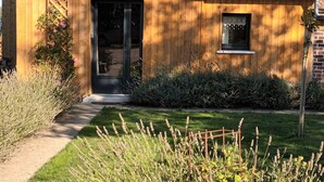 A wooden building with a door and window, surrounded by a garden with lavender plants. - La chouett'chambre" bed and breakfast (Les Hermites)