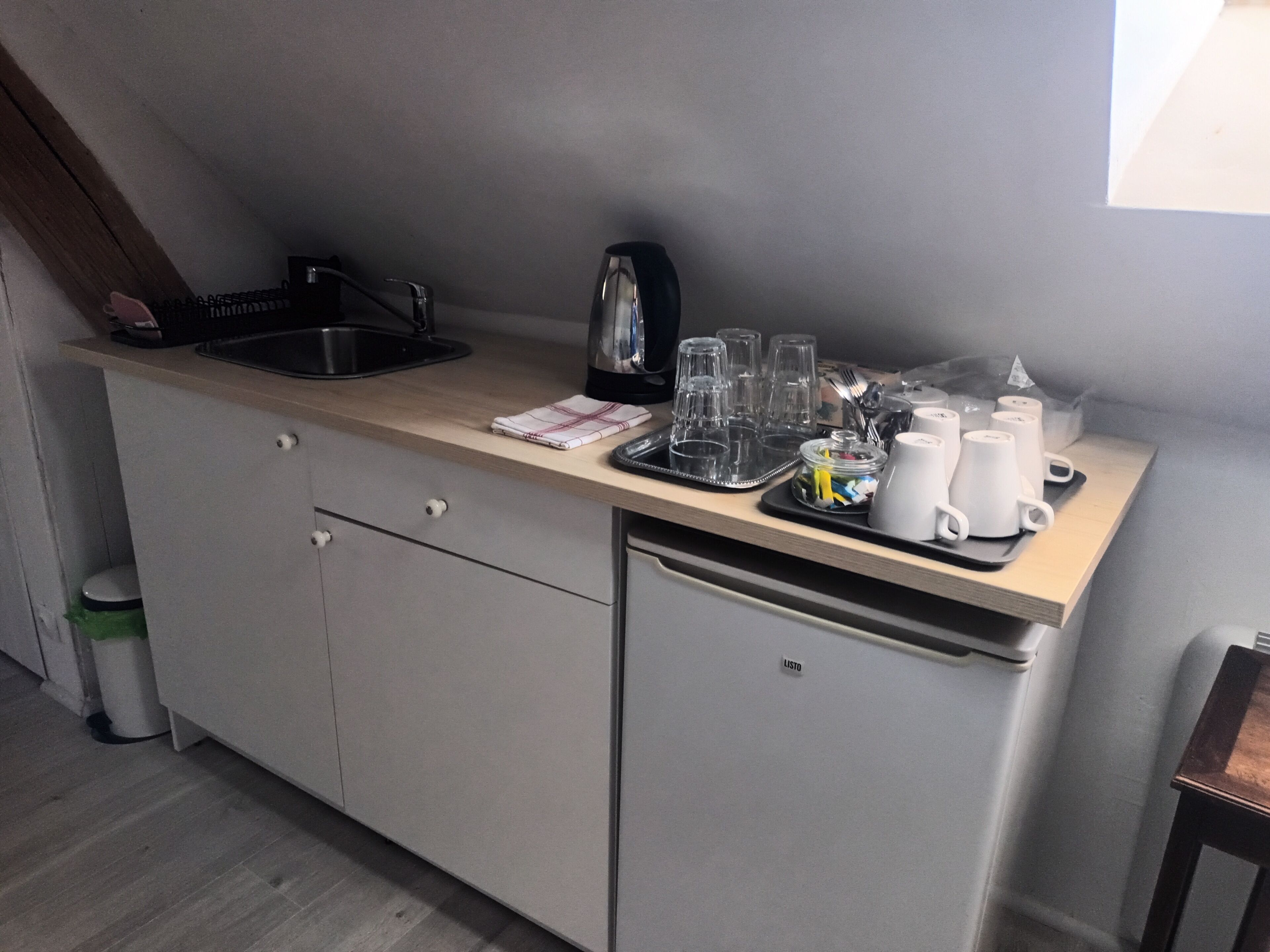 A compact kitchenette with a sink, coffee maker, and various glassware.