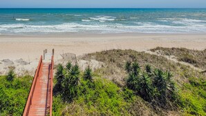 A beach with a wooden boardwalk leading to the shore, surrounded by green vegetation. - Sunny Turtle: Turtle-tastic Oceanfront Stay! (Surf City)
