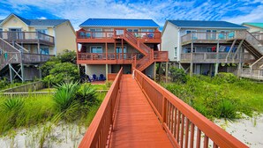 A wooden boardwalk leading to a beachfront property with multiple balconies and a sandy beach. - Sunny Turtle: Turtle-tastic Oceanfront Stay! (Surf City)