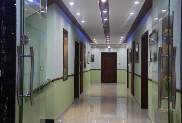 A corridor with glass walls, a polished floor, and a series of doors.