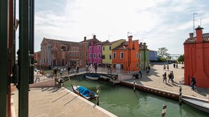 A canal with colorful buildings and a bridge. - Wondrous Palazzetto 1619 in Magical Burano Island (Burano)
