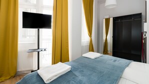Een hotelkamer met een bed, een televisie, een kledingkast en gele gordijnen.