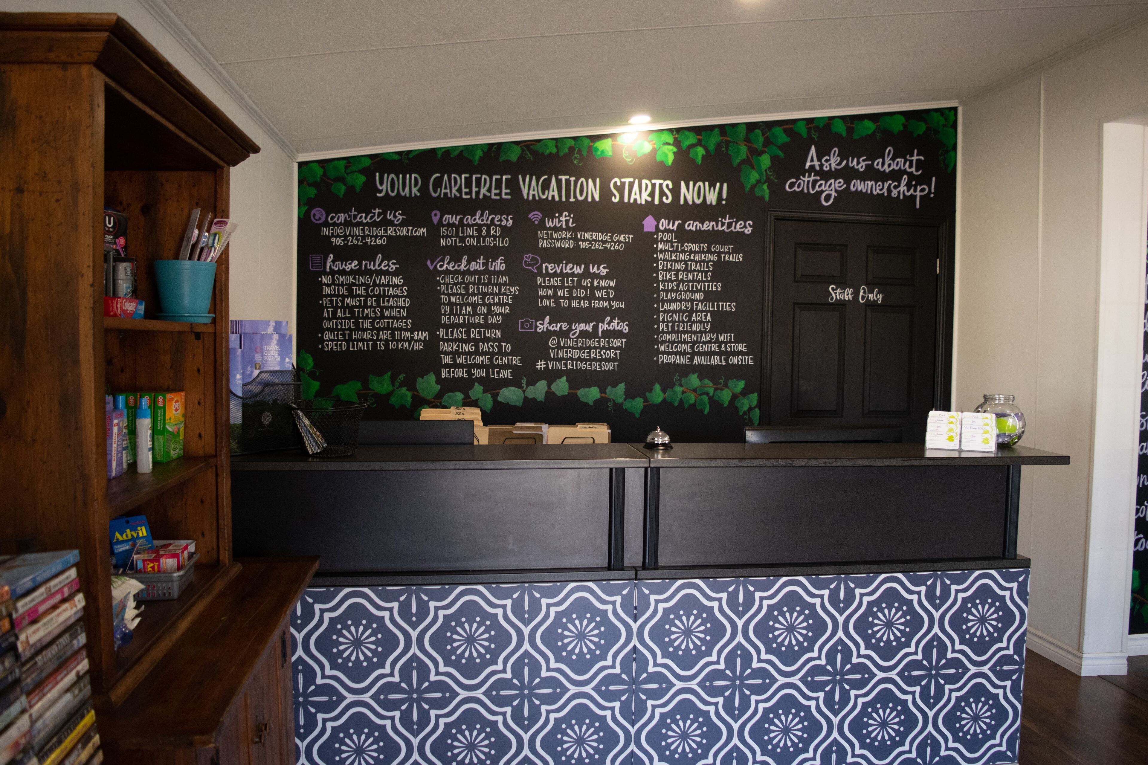 A reception desk with a chalkboard displaying information about a vacation rental, including amenities and rules.