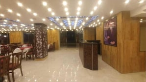 A restaurant with a modern interior, featuring wooden paneling, a central counter, and a ceiling with recessed lighting. - Rendezvous hotel petra (Wadi Musa)
