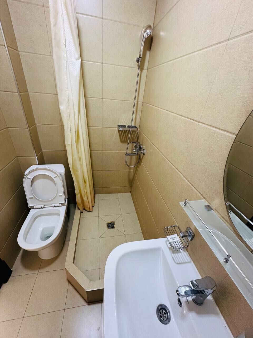 Un baño pequeño con azulejos, que incluye inodoro, ducha y lavamanos.