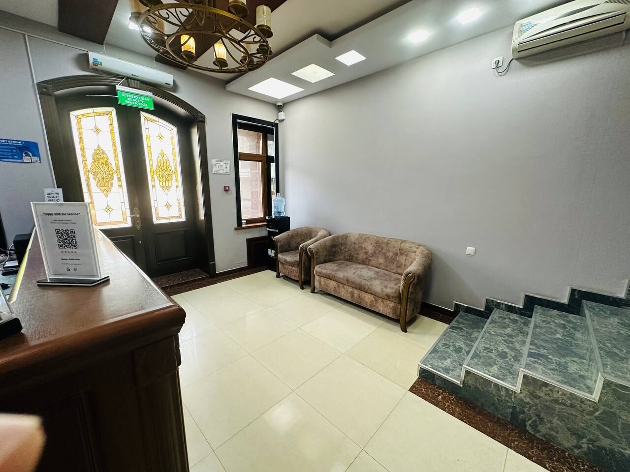 A reception area with a reception desk, a sofa, a staircase, and a water dispenser.