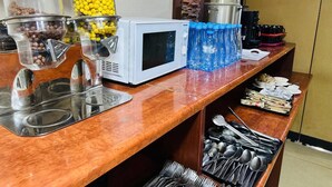 A kitchen area with a microwave, food dispensers, and a water dispenser. - Western Hotel (Tashkent)