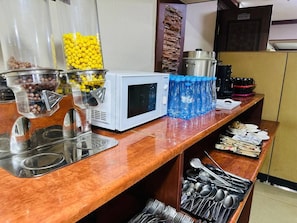 A kitchen area with a microwave, food dispensers, and a water dispenser. - Western Hotel (Tashkent)