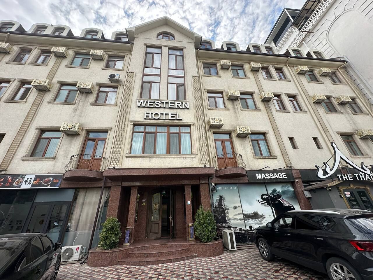 A Western Hotel with a central entrance, a massage service, and a visible car parked in front.