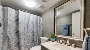 A bathroom with a marble shower curtain, a toilet, a sink with a mirror, and a towel rack. - GP56 -  Stylish 3BD Condo | Six Flags| Grand Prairie (Grand Prairie)