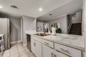 A modern kitchen with a marble countertop, stainless steel appliances, and a built-in sink. - GP56 - Stylish 3BD Condo | Six Flags | Workspace (Grand Prairie)