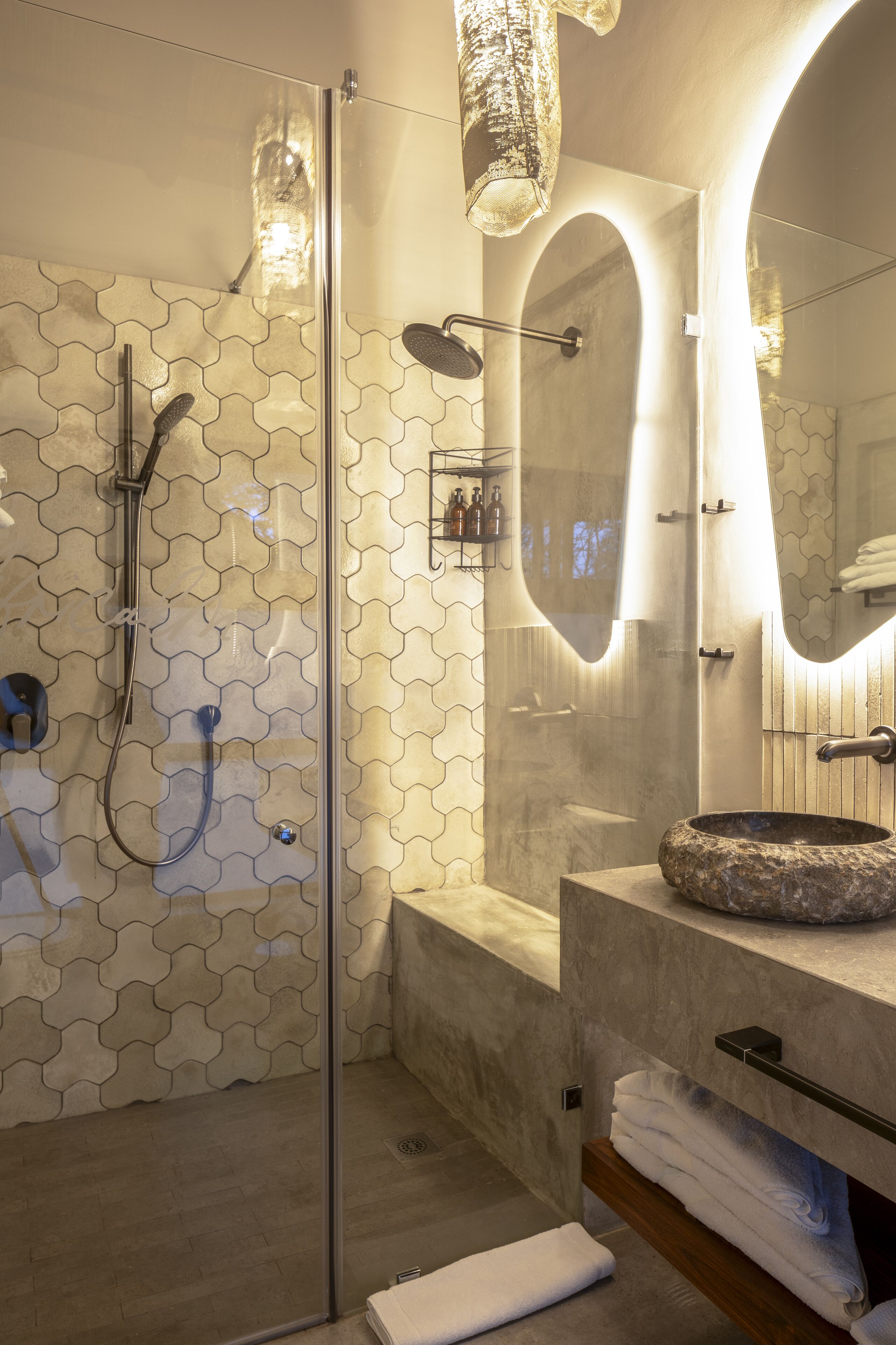 A modern bathroom with a glass-enclosed shower, a marble sink, and a large mirror.