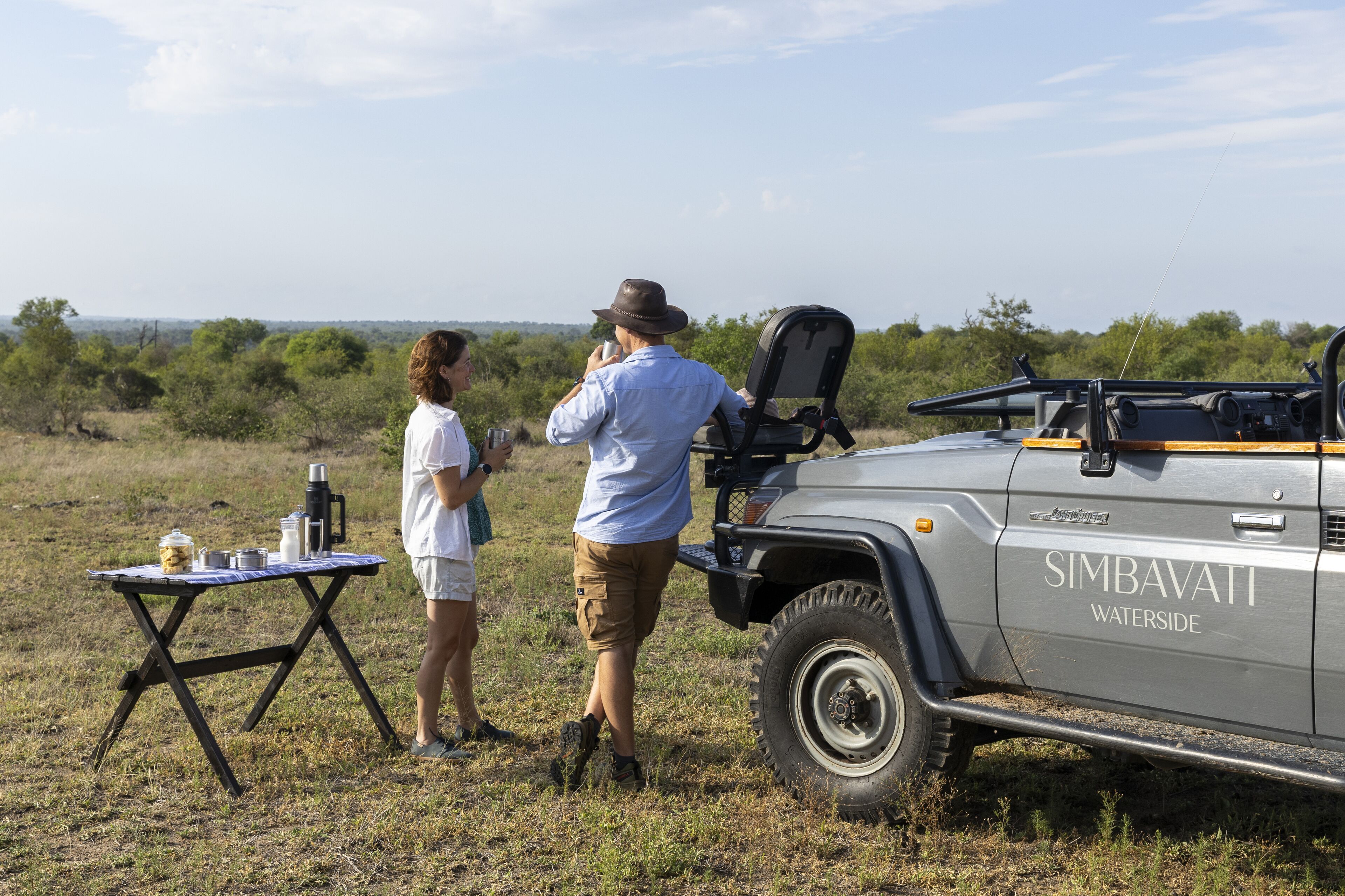 Un véhicule de safari portant l’inscription « SIMBAVATI WATERSIDE » était garé dans une zone herbeuse, à proximité d’une table qui avait été installée.