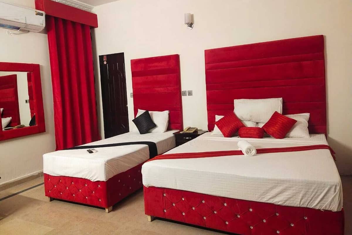 Habitación de hotel con dos camas, cabeceros rojos y una cortina roja.