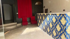A room with a stage area, red curtains, and a patterned wall. - Hotel Royal Grand (Mekhtar)