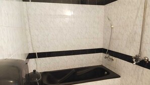 A bathroom with a black bathtub, a toilet, and a shower. - Hotel Royal Grand (Mekhtar)