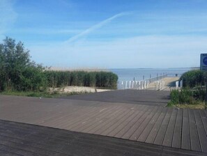 A wooden boardwalk leading to a beach with a clear view of the ocean.