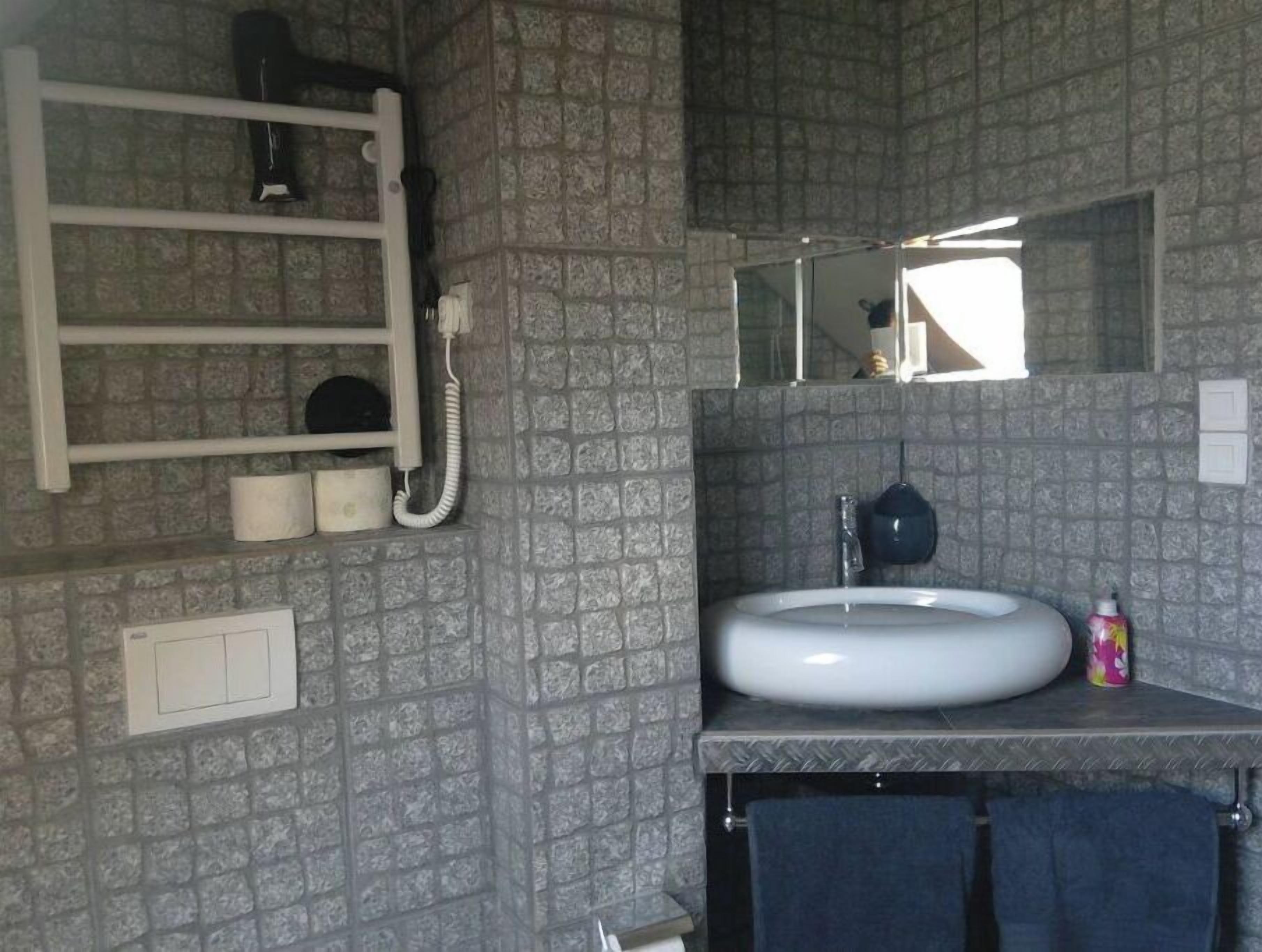 Une salle de bain avec un lavabo blanc, un miroir, un porte-serviettes et un téléphone.