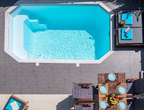 A rooftop pool with a dining area and lounge chairs.