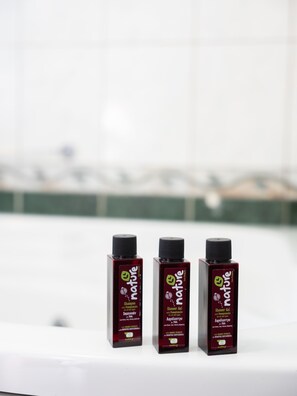 Three bottles of Nature brand shampoo and shower gel on a white surface.