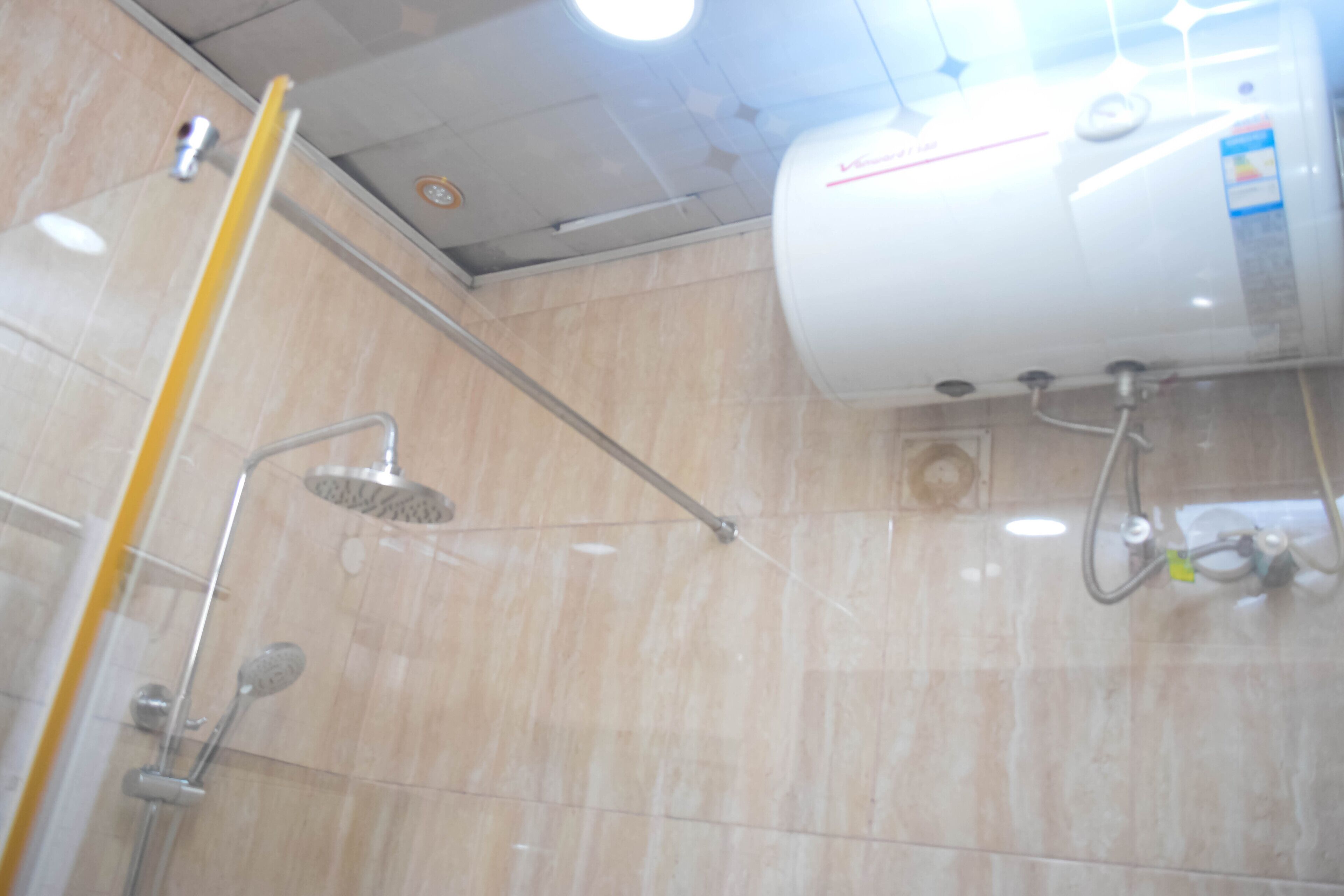 A shower area with a handheld showerhead, a wall-mounted faucet, and a water heater.