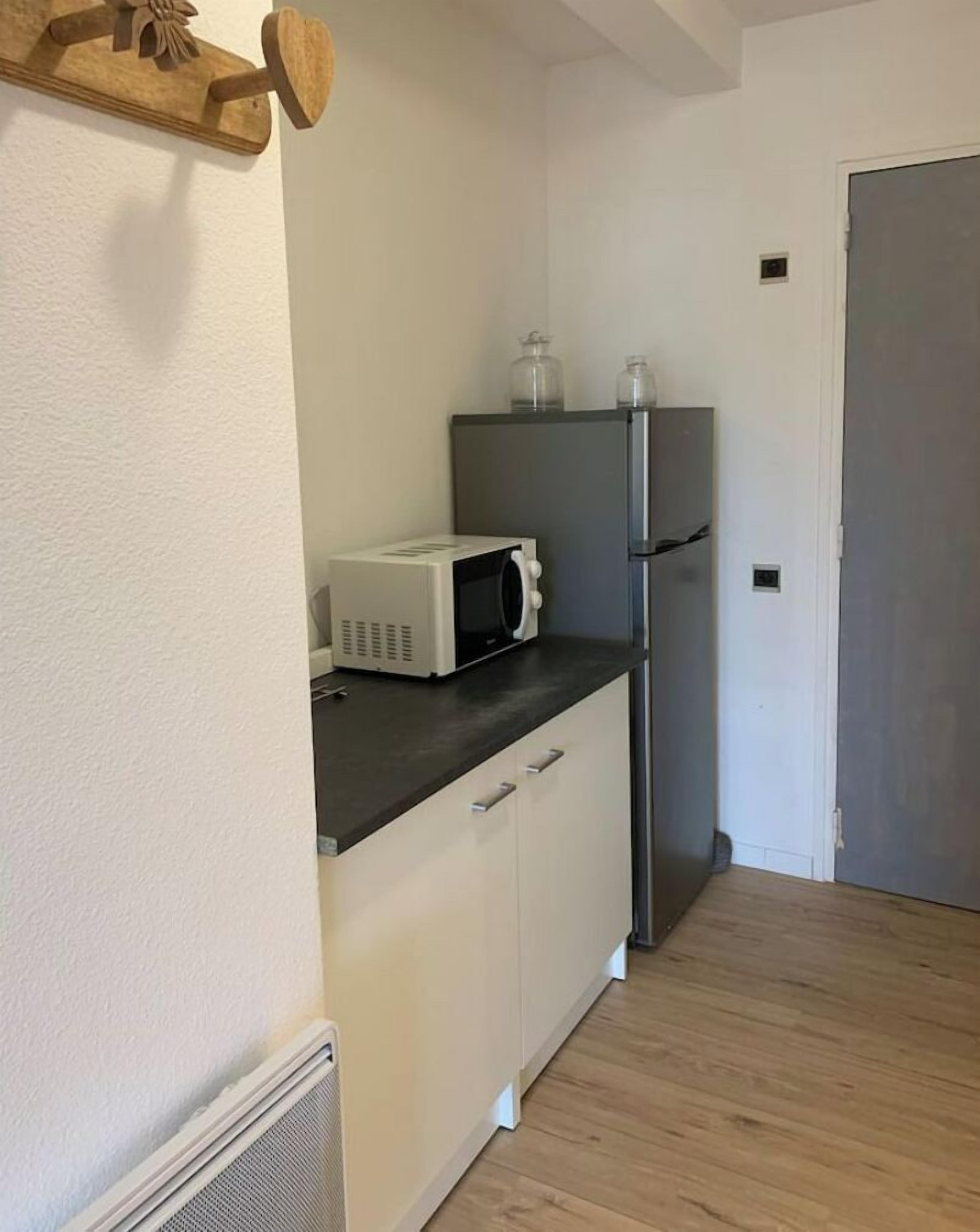 Eine kleine Küchenzeile mit Mikrowelle, Kühlschrank und einem Holzboden.