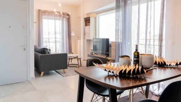 A modern living room with a sofa, a TV, and a dining table with decorative items. - Friendly Accommodation-GTD33701 (Athens)