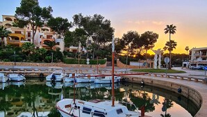 A marina with boats docked, surrounded by buildings and palm trees.