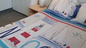Une chambre à coucher comprenant un lit, une table de chevet, une armoire et un luminaire fixé au mur.