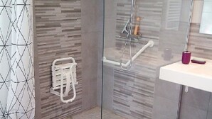 Une salle de bain moderne avec une douche à parois de verre, un lavabo blanc avec un miroir et des murs à motifs.