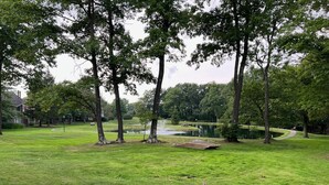 A park with a pond, picnic tables, and a walking path. - Cozy Ski Condo with Pond View (Hidden Valley)