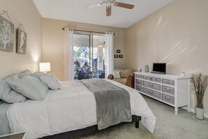 Une chambre à coucher avec un lit, une commode, un téléviseur et une vue sur l’extérieur.