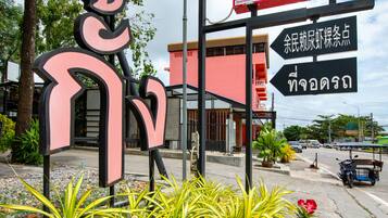 A sign for OYO M&C Garden Resort & Restaurant with directional arrows and Thai text.