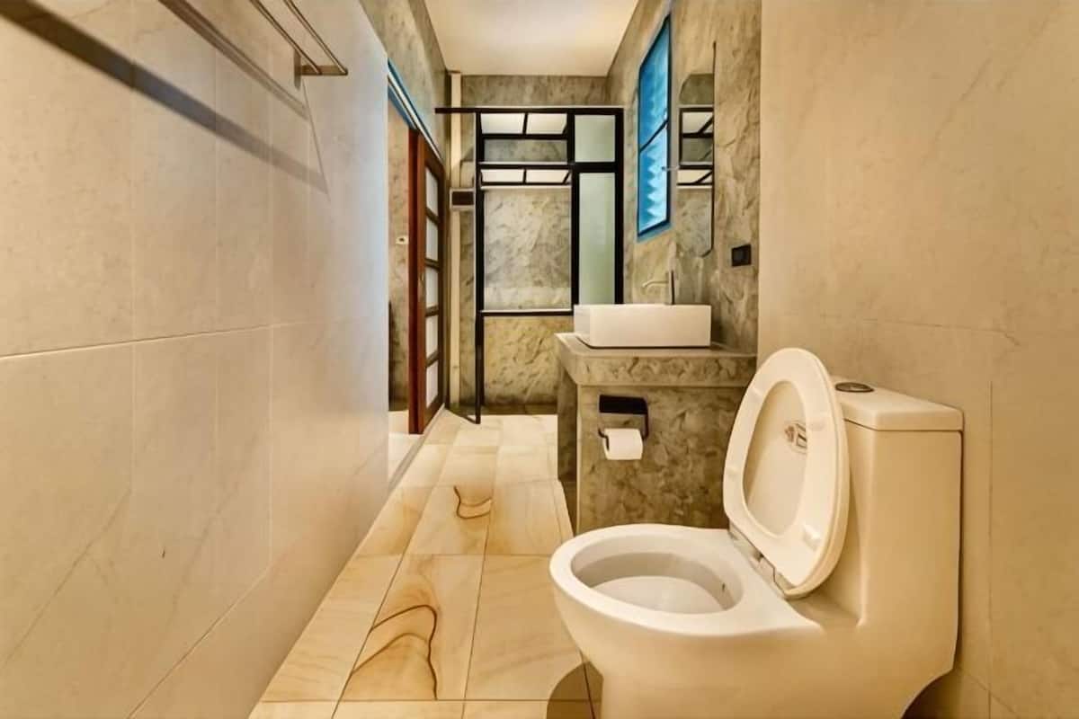 A bathroom with a toilet, sink, and marble walls.