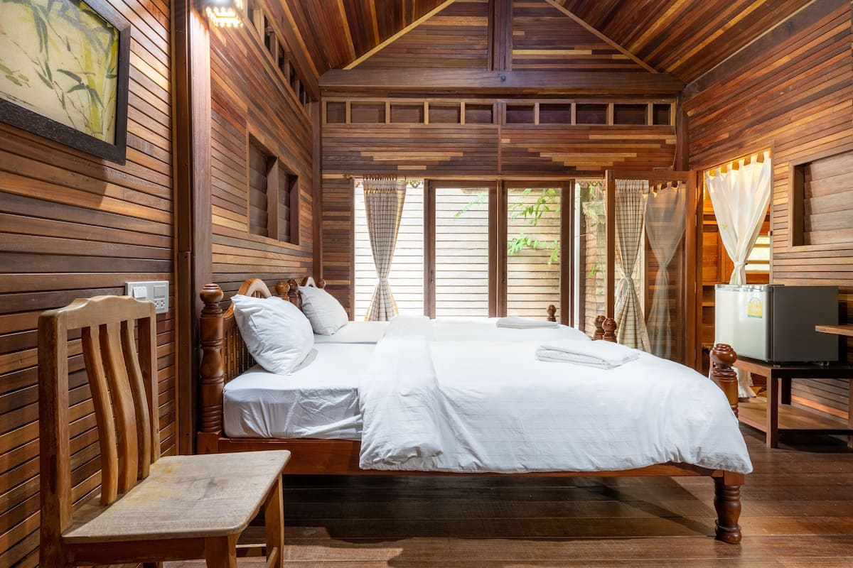 A wooden room with a bed, a chair, and a television.