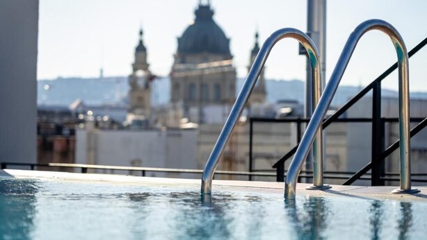 A rooftop pool with metal railings and a view of a historic building in the background. - SWU Magazine Rooms (Budapest)