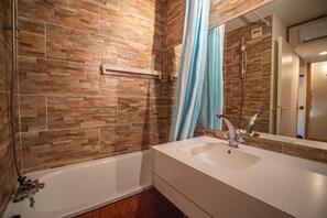 Un bagno con vasca, lavandino e doccia.
